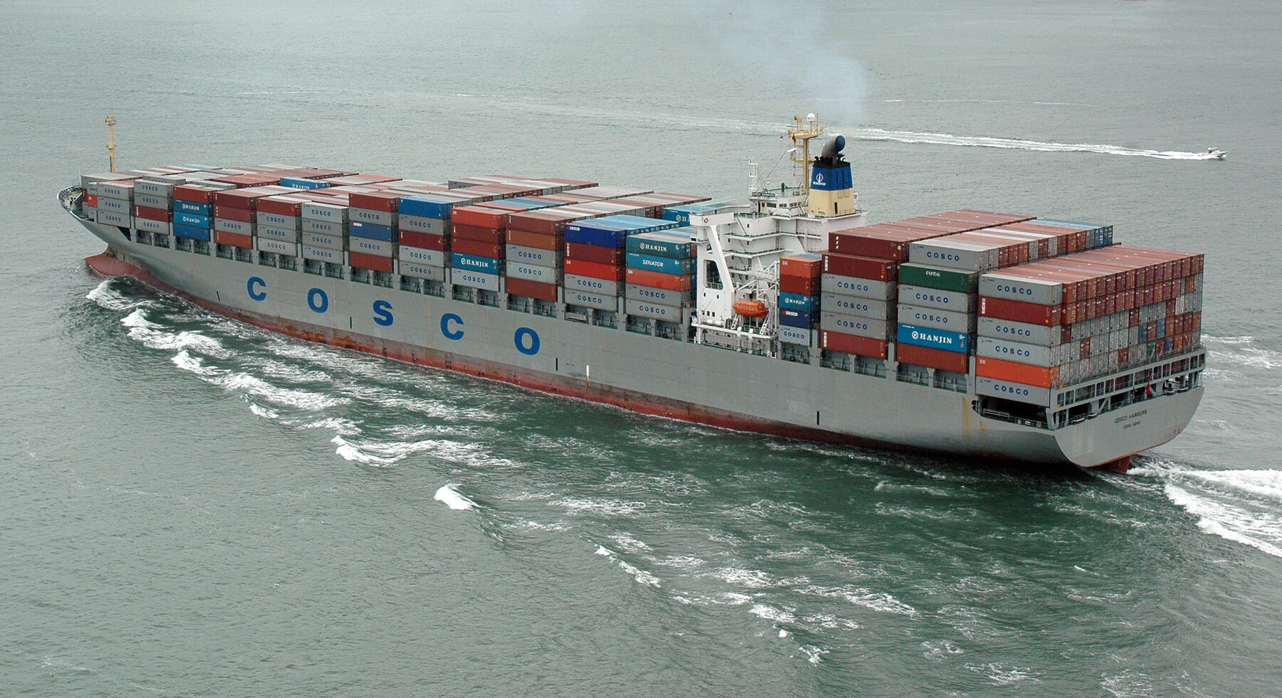 The COSCO Hamburg container ship sails through San Francisco Bay with stacks of cargo containers aboard.